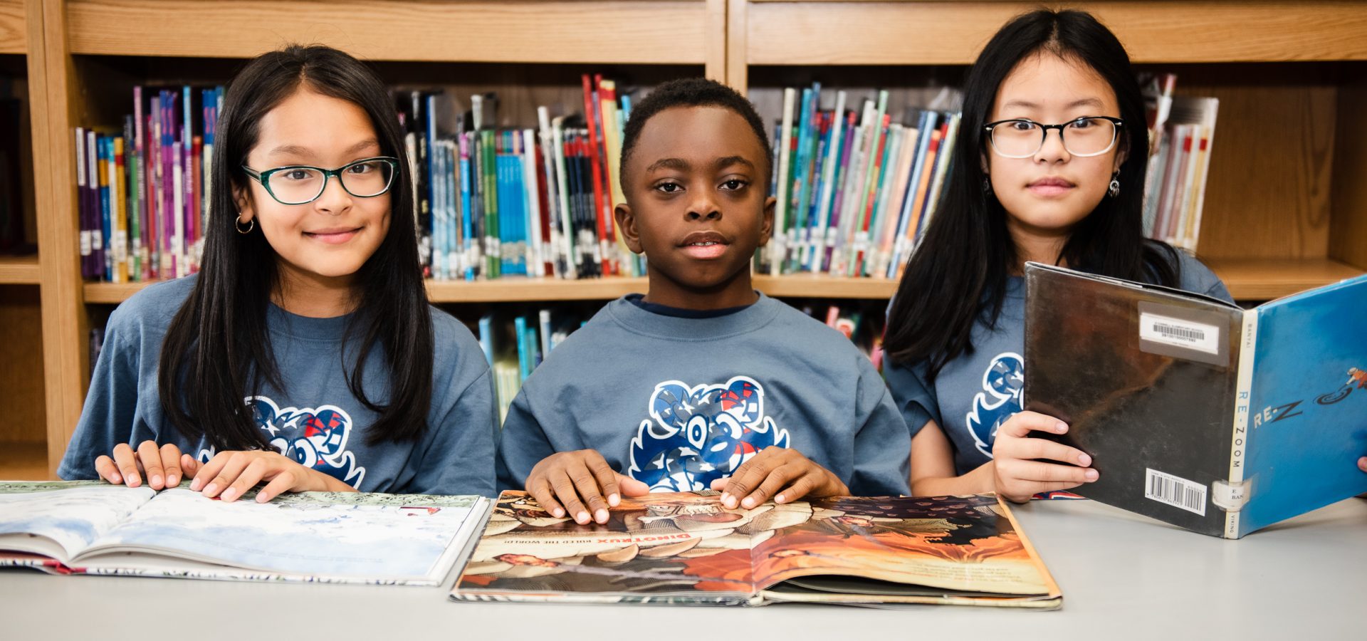 three children at table in school library