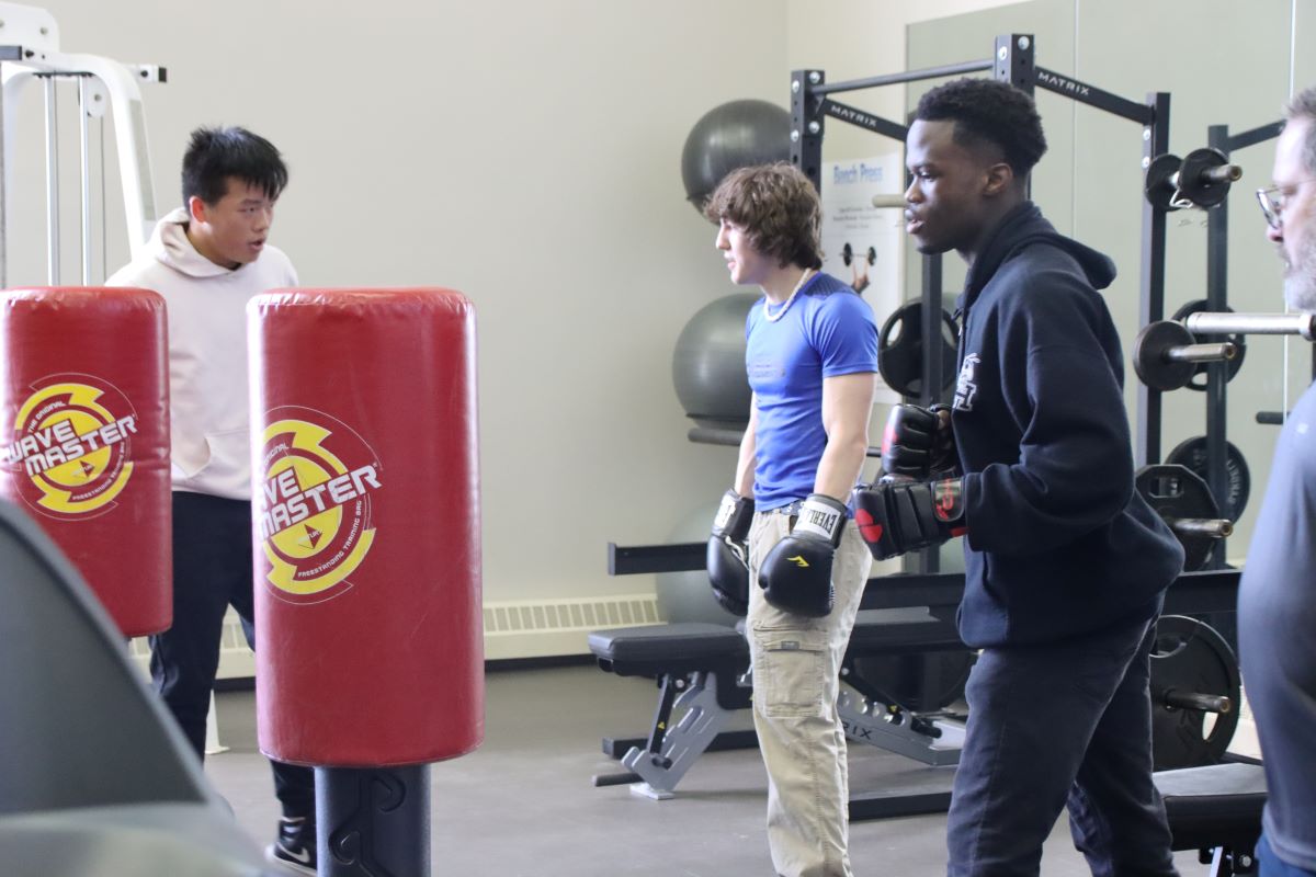 three teens wear boxing gloves near punching bags