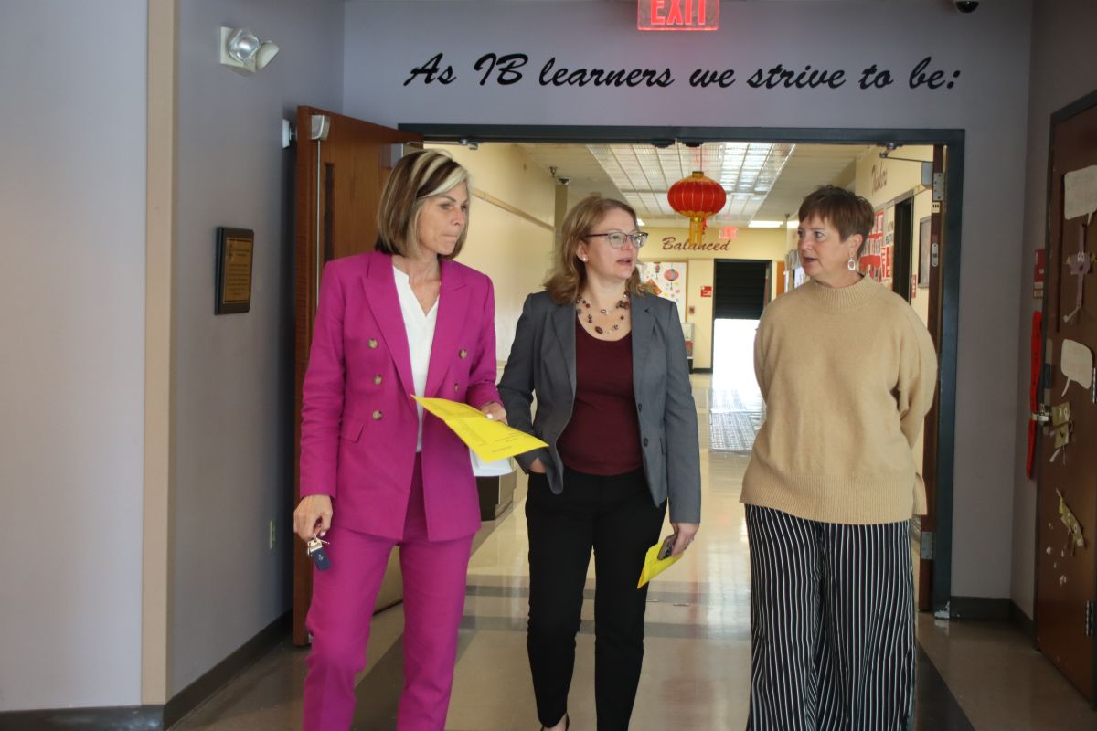 Three women walk down a school hallway