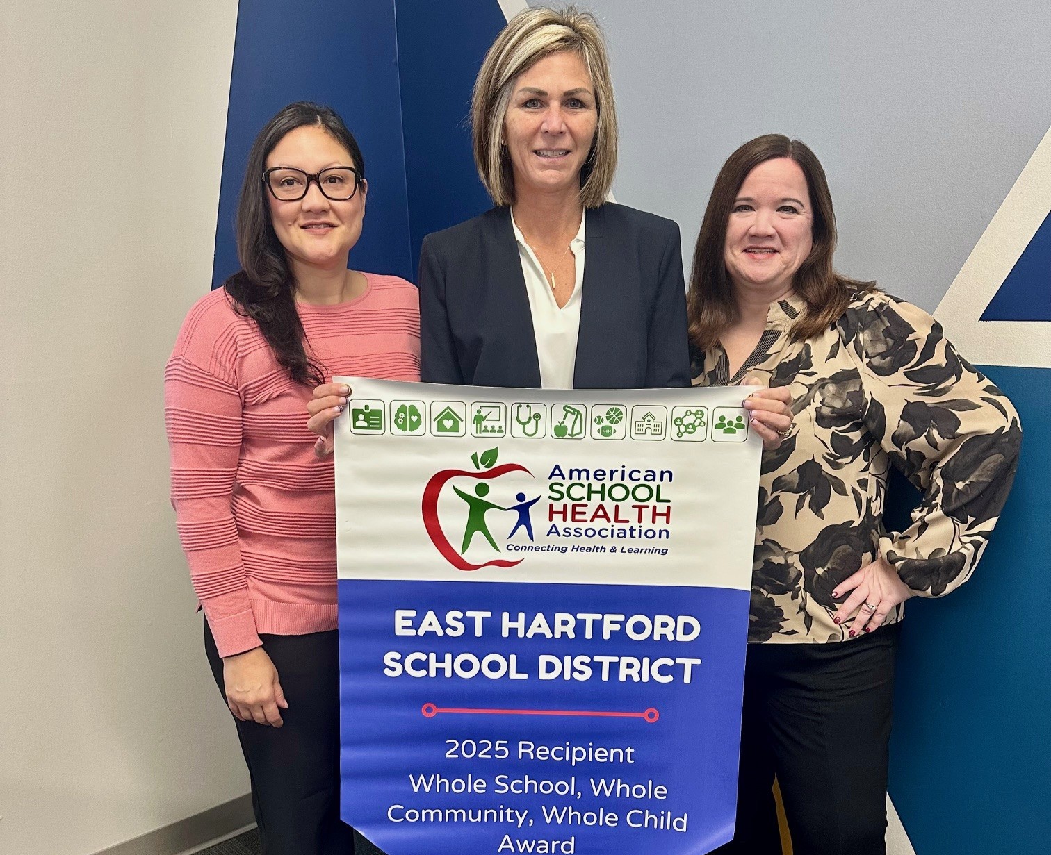 Assistant Superintendent Elsie Torres, Tracy Stefano, and Assistant Superintendent Ellen Delgado stand with the 2025 WSCC Award banner.